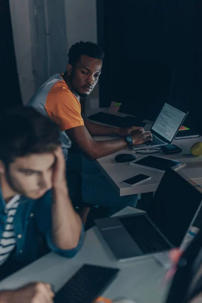 Two young multicultural programmers working at night in office — Stock Photo