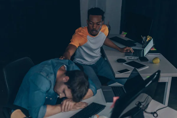 Young african american programmer awakening colleague at night in office — Stock Photo