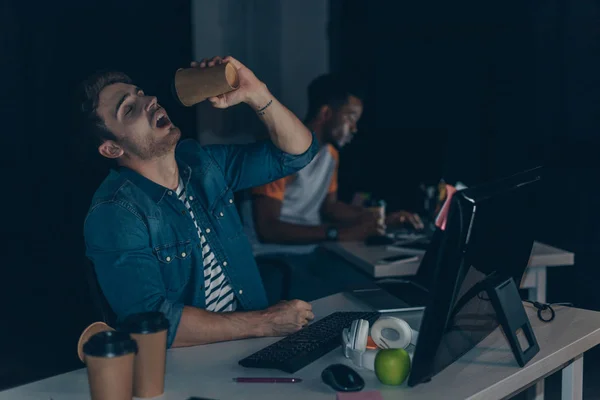 Foco seletivo do jovem programador que bebe café para se aproximar do colega afro-americano — Fotografia de Stock