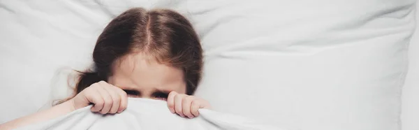 Panoramic shot of scared child hiding under blanket — Stock Photo