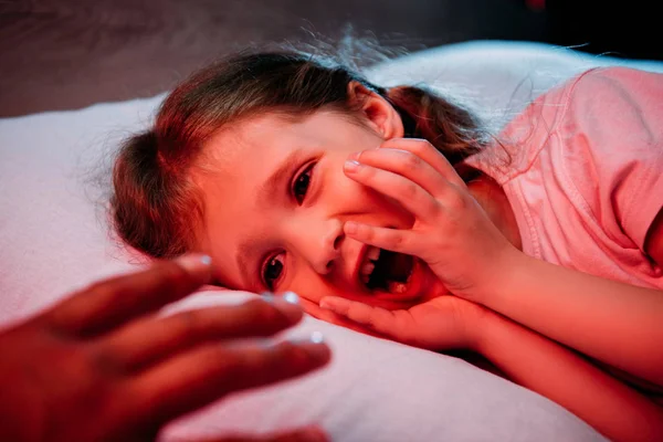 Male hand near frightened, screaming child lying in bed — Stock Photo