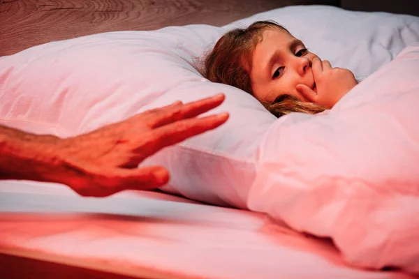 Male hand near frightened kid lying in bed and showing hush sign — Stock Photo