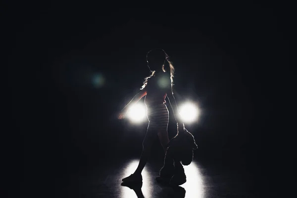 Child walking in darkness illuminated with headlights on black background — Stock Photo