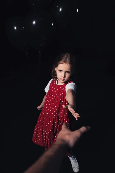 Cropped view of man outstretching hand to sad child isolated on black — Stock Photo