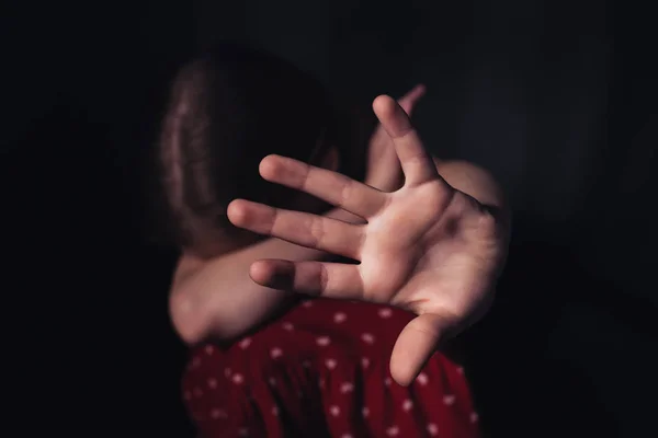 Selective focus of frightened, lonely child sitting with outstretched hand isolated on black — Stock Photo