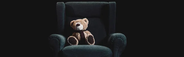 Панорамный снимок плюшевого медведя в сером кресле, изолированном на черном — стоковое фото