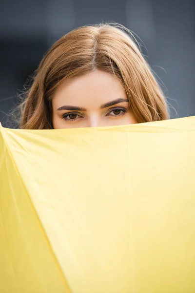 Vista cortada de mulher atraente com guarda-chuva amarelo fora — Fotografia de Stock