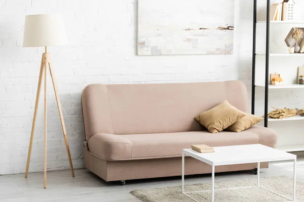 Interno della camera con divano e cuscini, lampada, tavolo bianco — Foto stock
