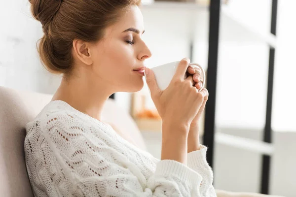 Vue latérale de la femme attrayante en pull blanc tenant tasse — Photo de stock