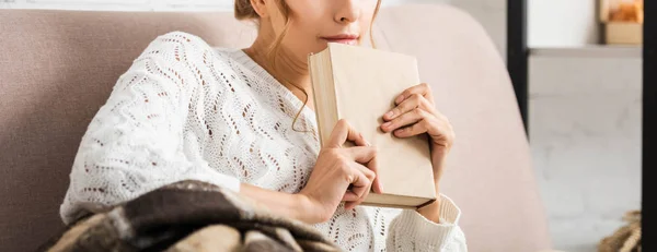 Vue recadrée de femme en chandail blanc tenant livre — Photo de stock