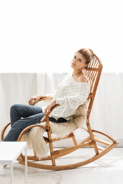 Attraktive Frau im weißen Pullover sitzt auf Schaukelstuhl — Stock Photo