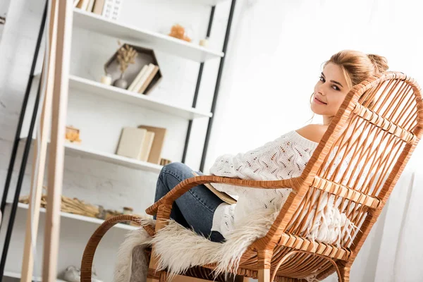 Attraktive Frau im weißen Pullover sitzt auf Schaukelstuhl — Stockfoto