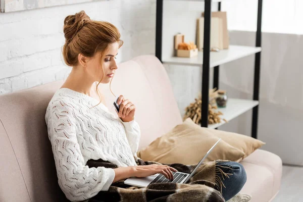 Attractive woman in white sweater holding credit and laptop — Stock Photo