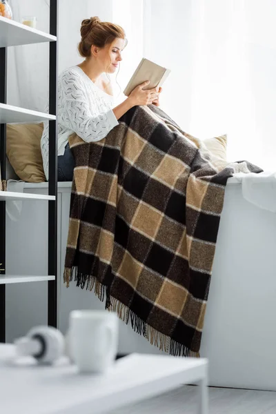 Attraktive Frau im weißen Pullover mit Decke Lesebuch — Stockfoto