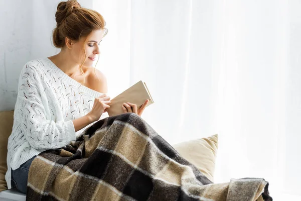 Mulher atraente em camisola branca com livro de leitura cobertor — Fotografia de Stock