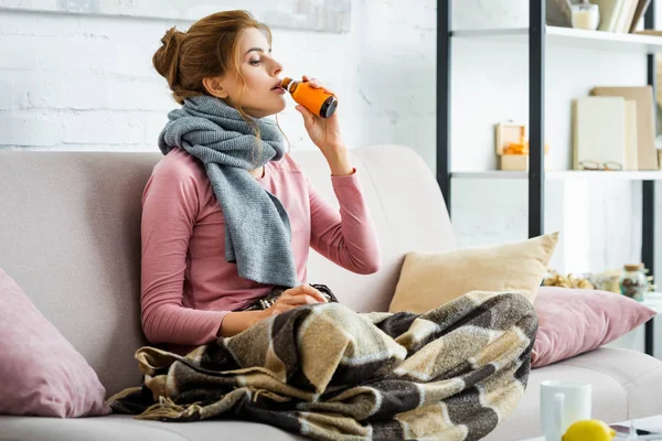 Attractive and ill woman with grey scarf drinking cough syrup — Stock Photo