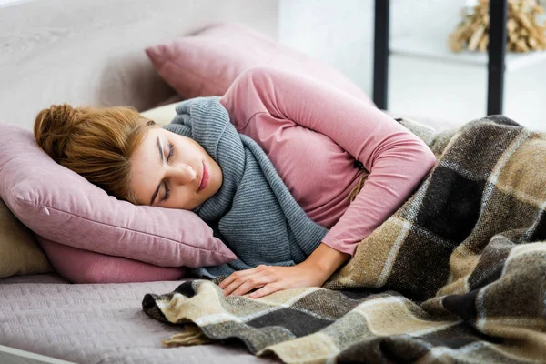 Attractive and ill woman with grey scarf sleeping on bed — Stock Photo
