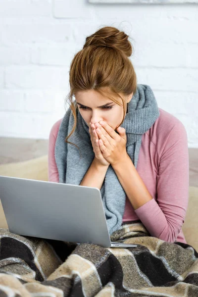Приваблива і шокована жінка з сірим шарфом тримає ноутбук — стокове фото