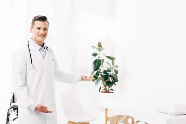 Médecin souriant en manteau blanc avec stéthoscope en clinique — Photo de stock