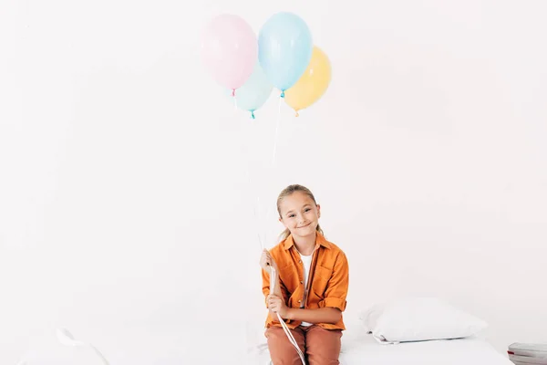 Niño sosteniendo globos de colores y sonriendo en el hospital - foto de stock