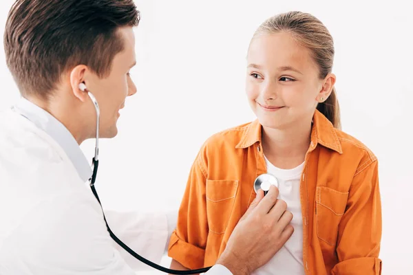 Pediatrist in white coat examining kid with stethoscope isolated on white — Stock Photo