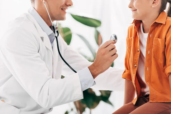 Vue partielle du pédiatre en manteau blanc examinant enfant avec stéthoscope — Photo de stock