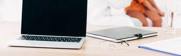 Panoramic shot of pediatrist examining child and laptop with blank screen on foreground — Stock Photo