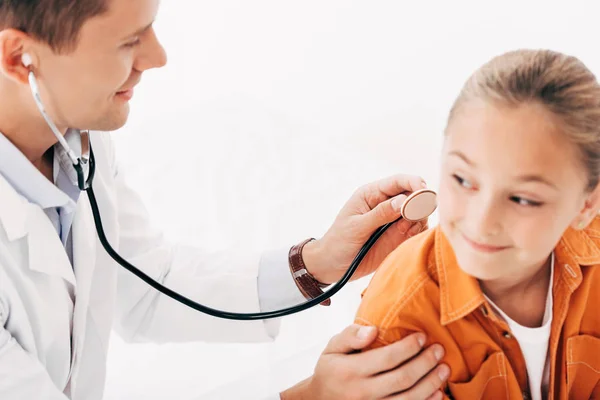 Kinderarzt im weißen Kittel untersucht Kind mit Stethoskop isoliert auf weißem Grund — Stockfoto