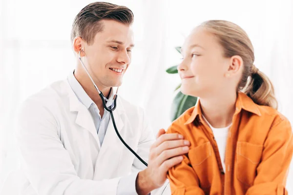 Pediatrist in white coat examining kid with stethoscope — Stock Photo