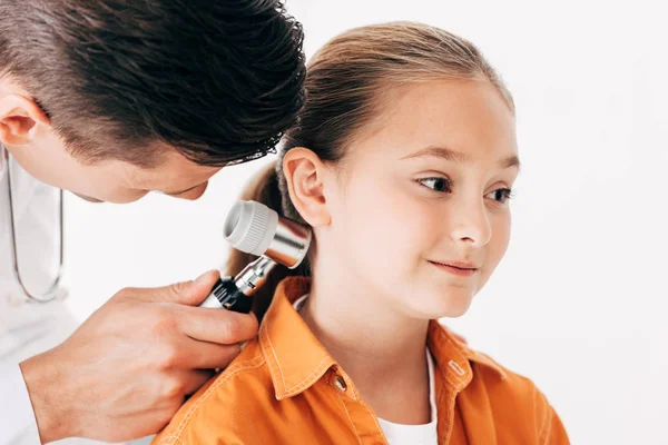 Pediatra concentrato in cappotto bianco esaminando bambino con dermascopio isolato su bianco — Foto stock