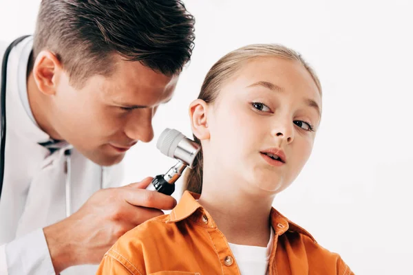 Pediatra enfocado en abrigo blanco examinando niño con dermascope aislado en blanco - foto de stock