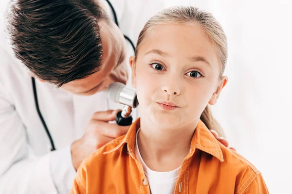 Fokussierter Kinderarzt im weißen Kittel untersucht Kind mit Dermaskop auf weißem Grund — Stockfoto