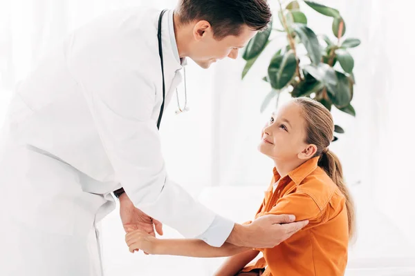 Pediatrist in white coat examining child in clinic — Stock Photo