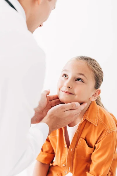 Vista recortada del pediatra en bata blanca examinando a un niño aislado en blanco - foto de stock