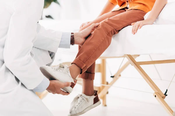 Cropped view of pediatrist in white coat examining child in clinic — Stock Photo