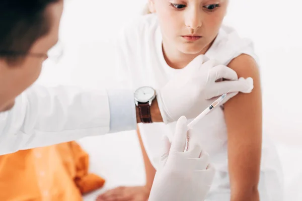 Partial view of pediatrist in latex gloves doing injection to child — Stock Photo