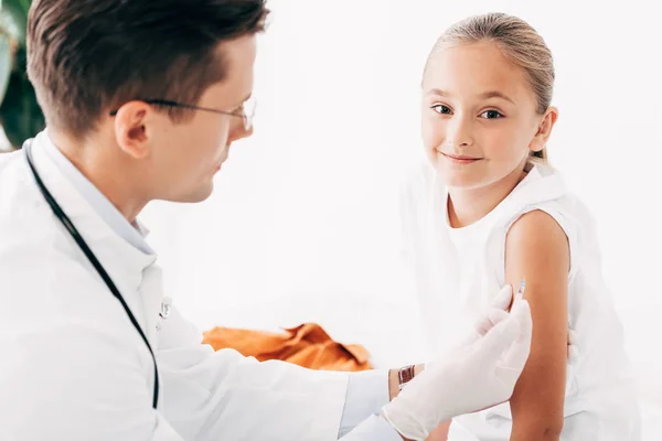 Enfoque selectivo del pediatra en guantes de látex inyectables al niño - foto de stock