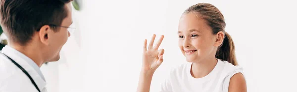 Panoramic shot of pediatrist and smiling child showing okay sign — Stock Photo