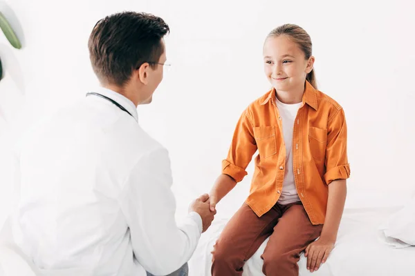 Pediatrist in white coat and child shaking hands in clinic — Stock Photo
