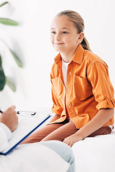 Teilansicht des Kinderarztes, der während der Untersuchung des Kindes in der Klinik in Klemmbrett schreibt — Stockfoto