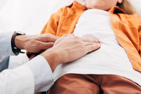Visão cortada de pediatra em casaco branco examinando criança na clínica — Fotografia de Stock