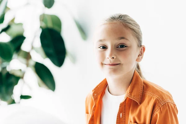 Cheerful kid in orange shirt looking at camera with smile — Stock Photo