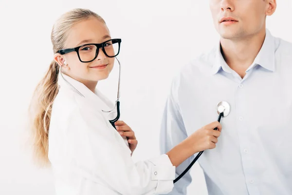 Niño en traje médico examinando paciente con estetoscopio - foto de stock