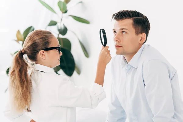 Child in doctor costume examining patient with magnifier — Stock Photo