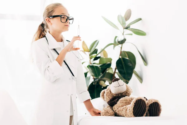 Enfant en costume de médecin et lunettes tenant la seringue — Photo de stock