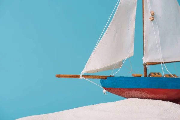 Close up view of decorative ship in white sand isolated on blue — Stock Photo