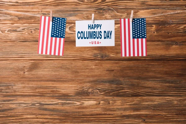 Card with happy Columbus day inscription between national flags of America on wooden surface — Stock Photo