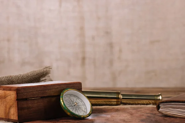 Brown wooden box near compass and golden telescope and piece of sacking — Stock Photo