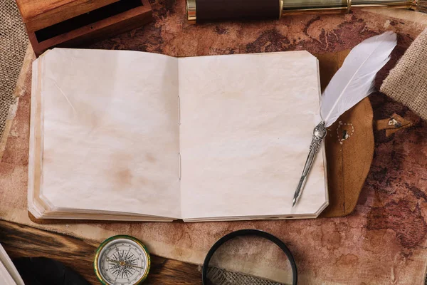 Livre ouvert avec des pages blanches et plume sur l'ancienne carte du monde — Photo de stock