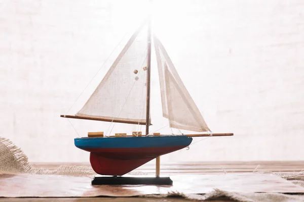 Barco decorativo con vela blanca en la superficie con hessian — Stock Photo